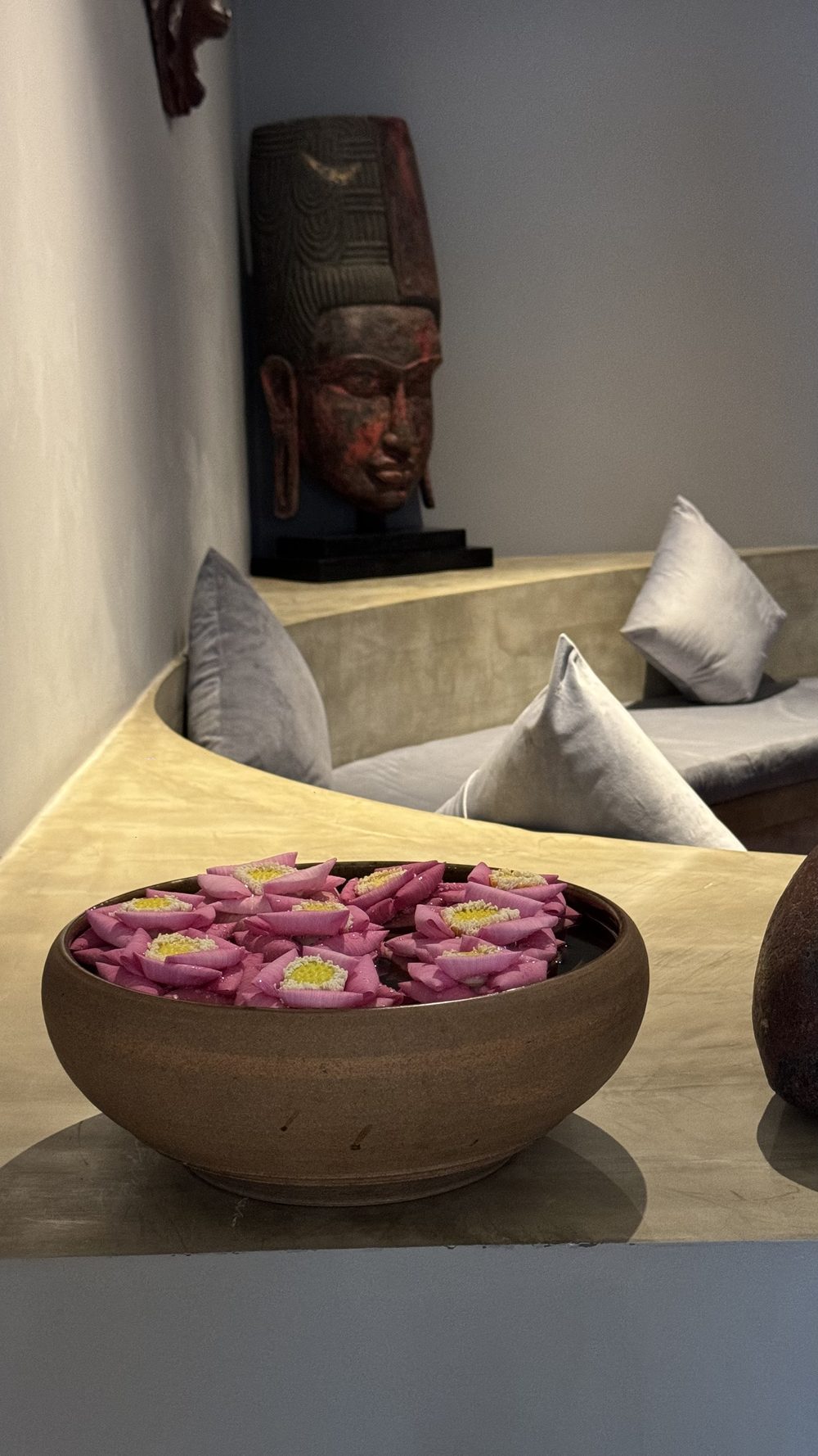 Lotus petals floating in a bowl beside pillows in a spa reception area