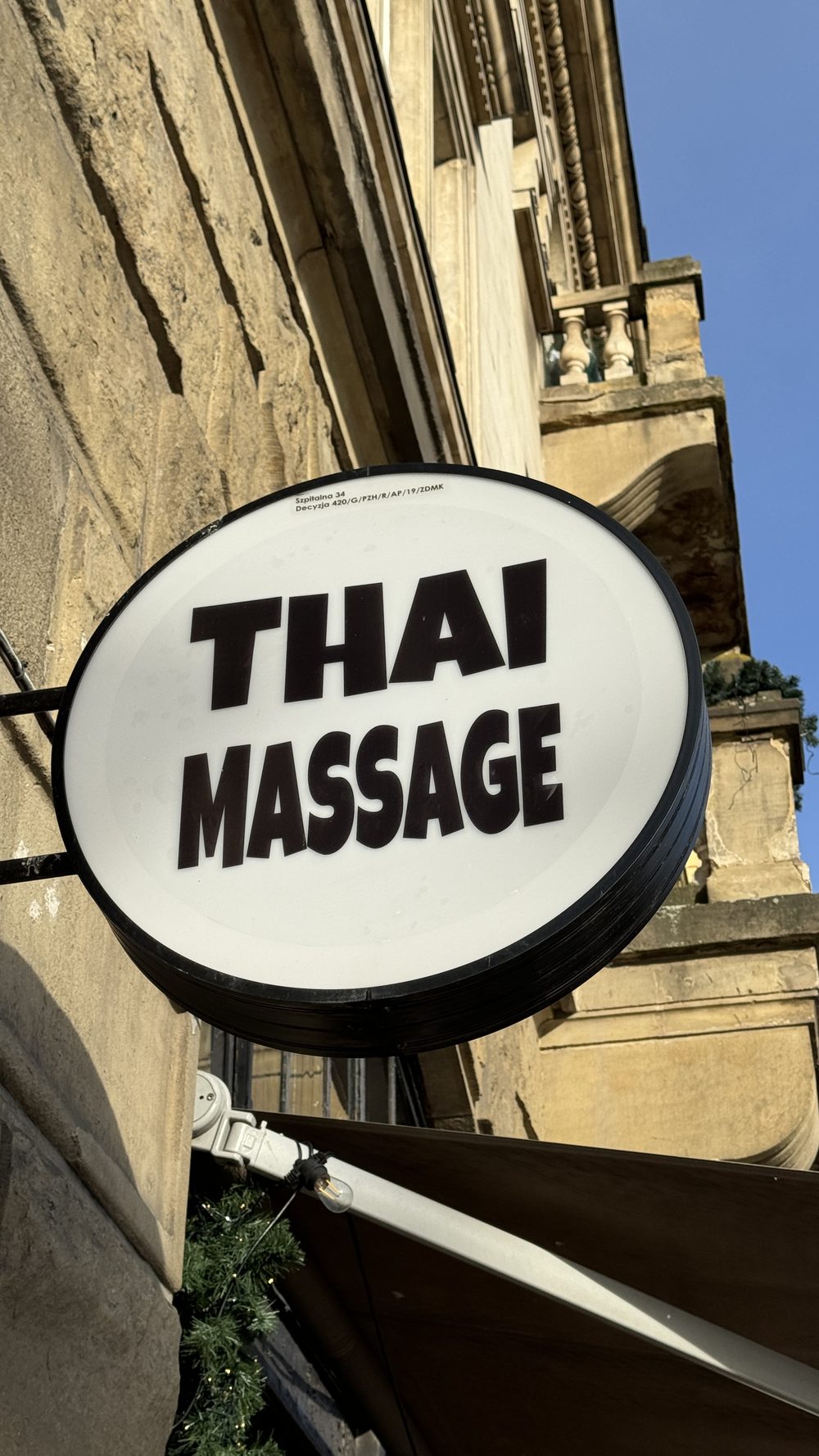 Round street sign reading Thai Massage