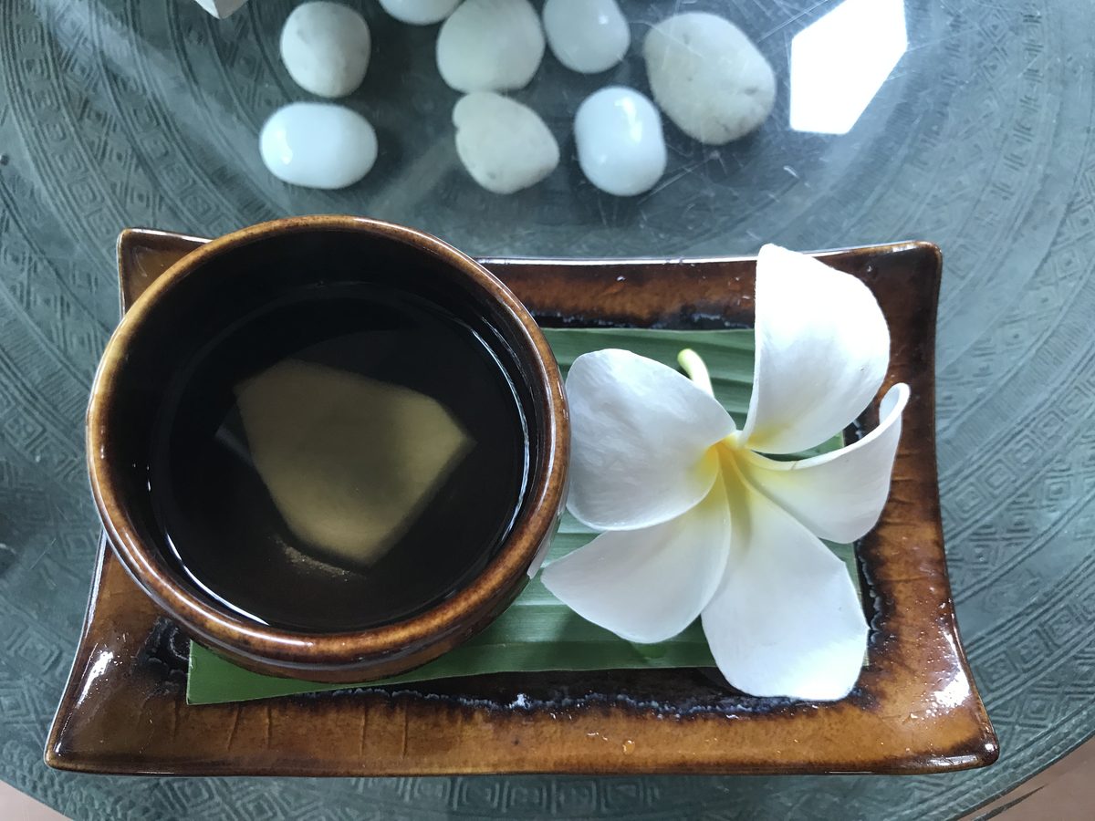 Welcome tea and a white frangipani flower on a tray at a spa